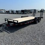 a black flatbed trailer is parked in a gravel lot