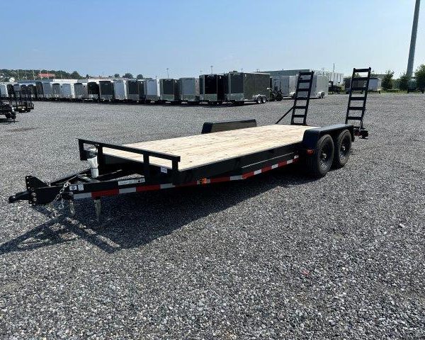 a black flatbed trailer is parked in a gravel lot