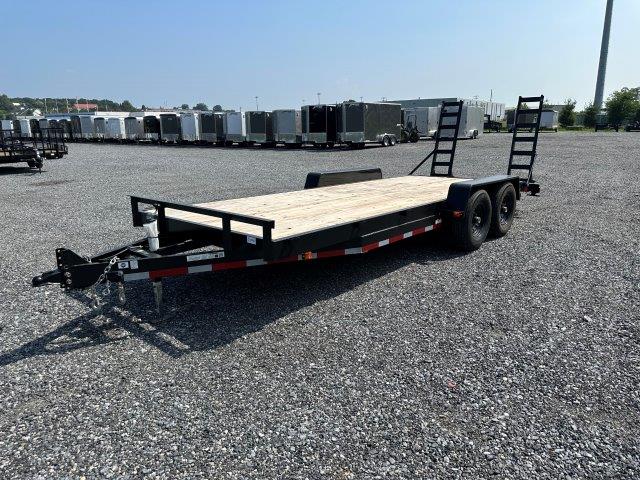 a black flatbed trailer is parked in a gravel lot