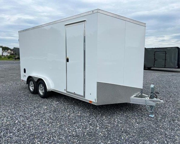 a white trailer is parked in a gravel lot .