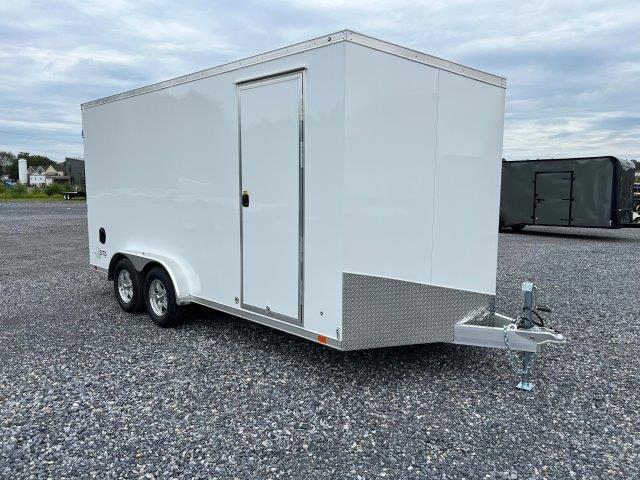 a white trailer is parked in a gravel lot .