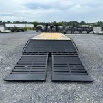 a CAM Superline flatbed trailer parked in a gravel lot