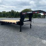 a CAM Superline flatbed trailer parked in a gravel lot