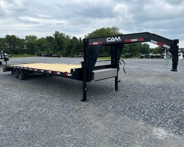 a CAM Superline flatbed trailer parked in a gravel lot