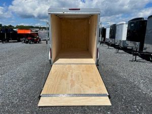an empty Car Mate trailer parked in a gravel lot