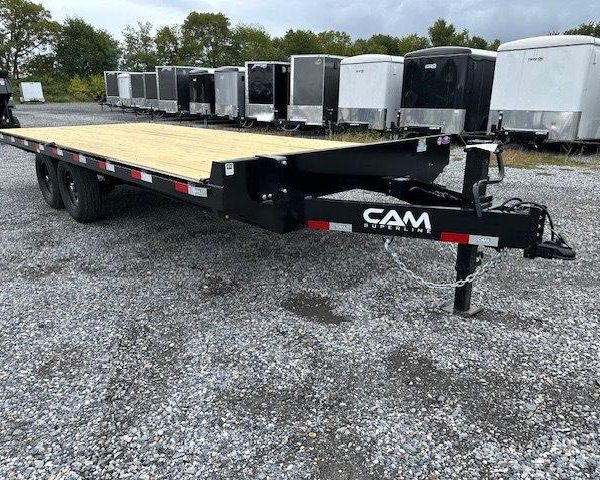 a flatbed trailer is parked in a gravel lot next to a row of trailers .