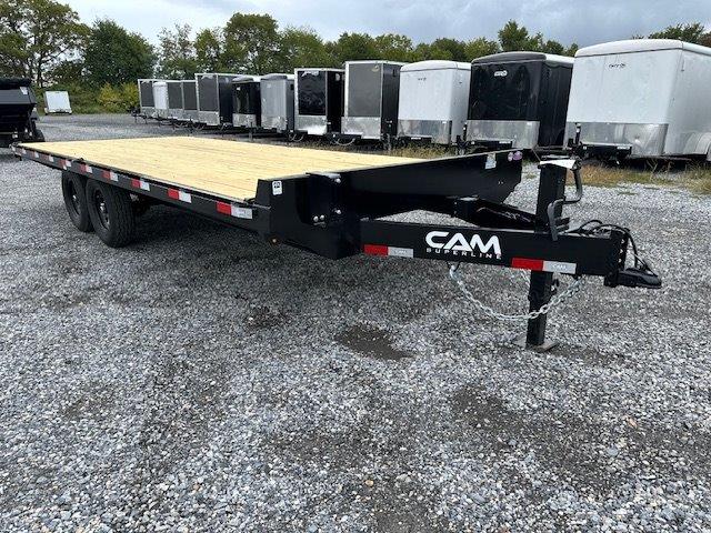 a flatbed trailer is parked in a gravel lot next to a row of trailers .