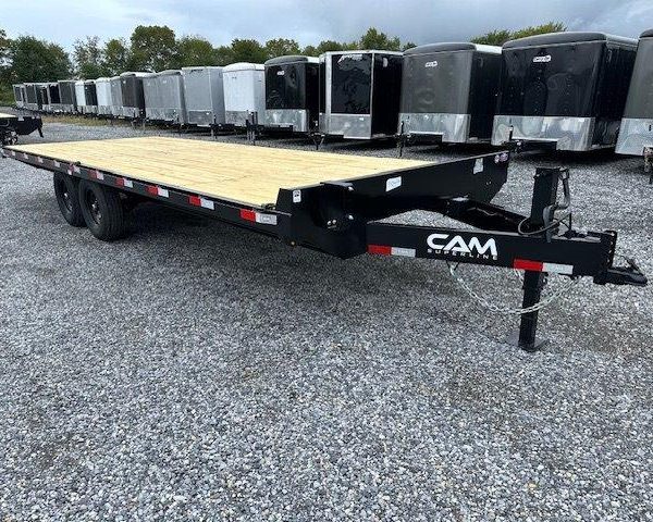 a flatbed trailer is parked in a gravel lot next to a row of trailers .