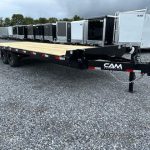 a CAM Superline flatbed trailer parked in a gravel lot