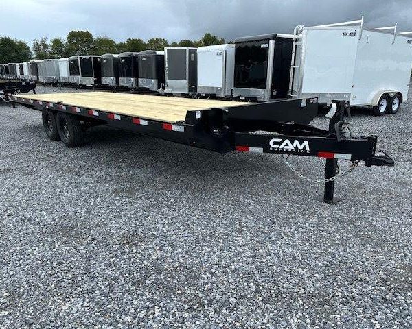 a CAM Superline flatbed trailer parked in a gravel lot