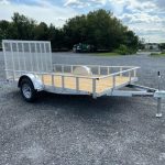 a Carry On trailer with a wooden deck parked in a gravel lot