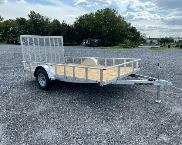 a Carry On trailer with a wooden deck parked in a gravel lot