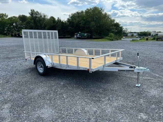 a Carry On trailer with a wooden deck parked in a gravel lot