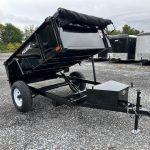 a dump trailer is parked in a gravel lot .