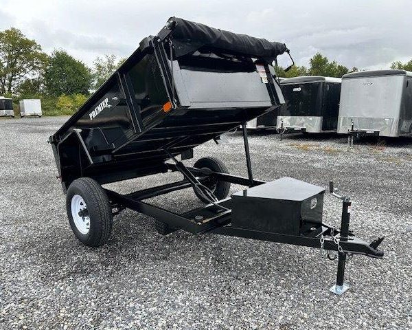 a dump trailer is parked in a gravel lot .