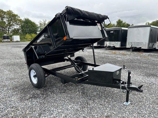 a dump trailer is parked in a gravel lot .