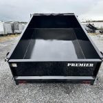 a black Premier dump trailer parked in a gravel lot