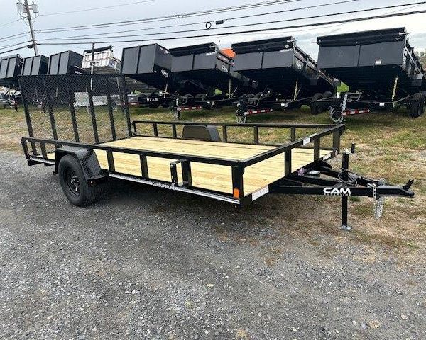 a trailer with a wooden deck is parked in a gravel lot .