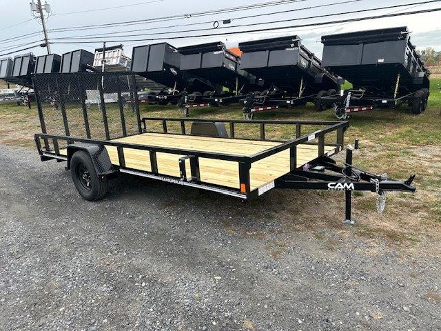 a trailer with a wooden deck is parked in a gravel lot .