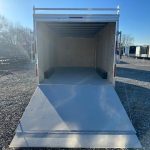 a white trailer is parked in a gravel lot with the door open .