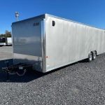 a white trailer is parked in a gravel lot .