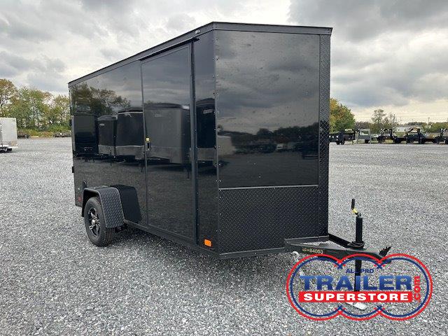 a black trailer is parked in a gravel lot .