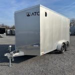 a silver trailer is parked in a gravel lot .