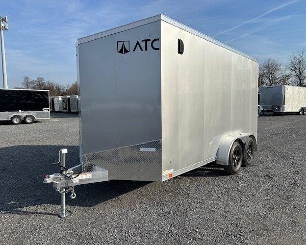 a silver trailer is parked in a gravel lot .