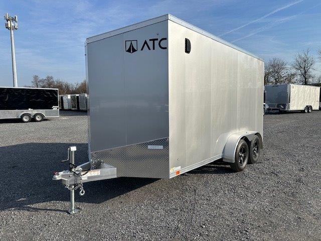 a silver trailer is parked in a gravel lot .