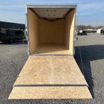 a trailer with the door open is parked in a gravel lot