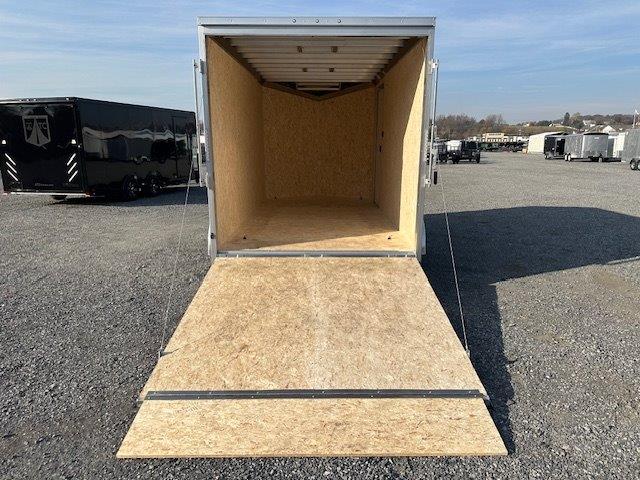 a trailer with the door open is parked in a gravel lot