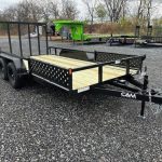 a trailer with a wooden deck is parked in a gravel lot .