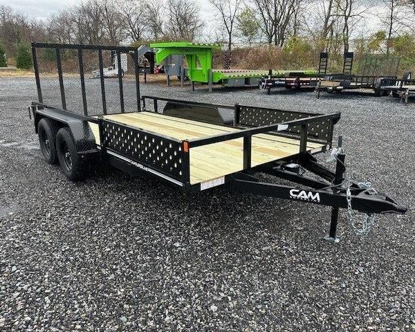 a trailer with a wooden deck is parked in a gravel lot .