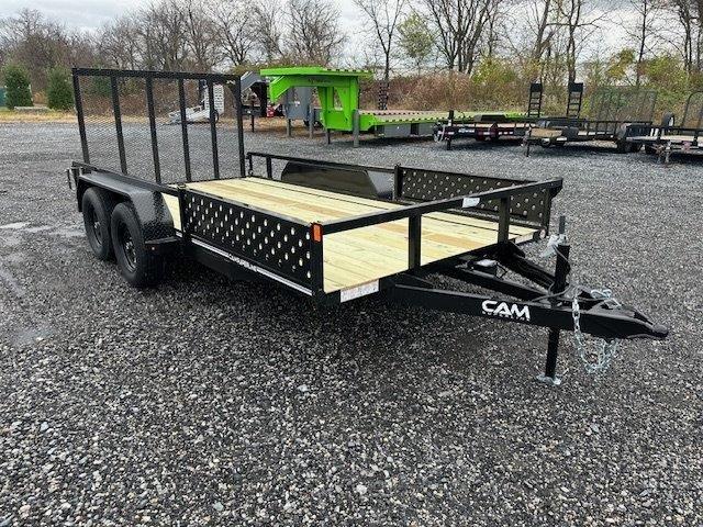a trailer with a wooden deck is parked in a gravel lot .
