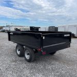 a black dump trailer parked in a gravel lot