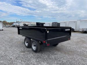a black dump trailer parked in a gravel lot
