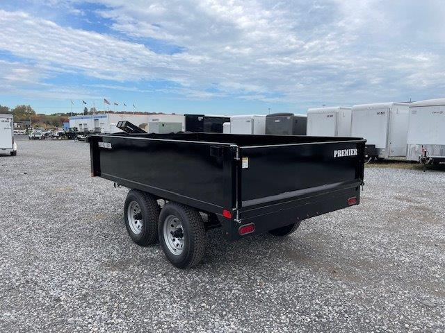 a black dump trailer parked in a gravel lot