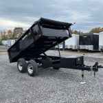 a black dump trailer parked in a gravel lot
