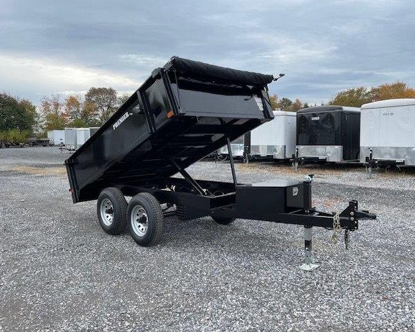 a black dump trailer parked in a gravel lot
