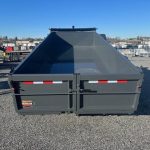 a large dump trailer is sitting on top of a gravel lot .