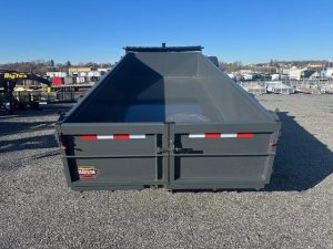 a large dump trailer is sitting on top of a gravel lot .