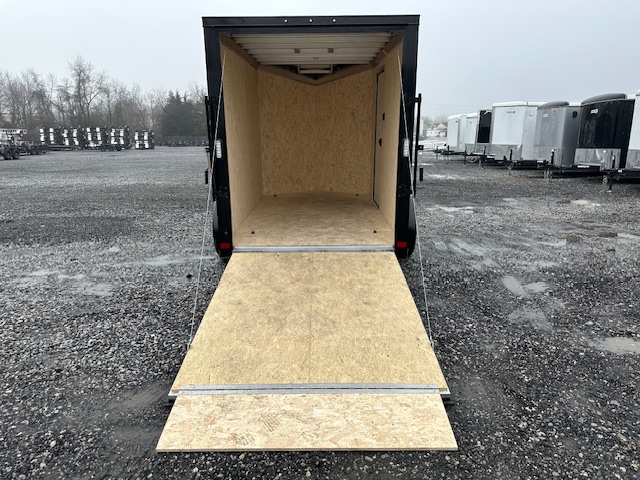 an atc trailer with the door open is parked in a gravel lot .
