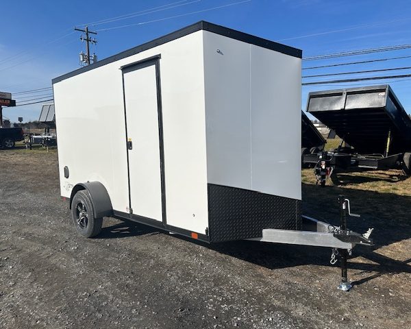 a white trailer with black trim is parked in a gravel lot
