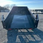 a dumpster trailer is parked in a gravel lot .