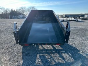 a dumpster trailer is parked in a gravel lot .