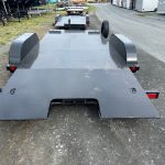 a black trailer is parked on the side of a road .