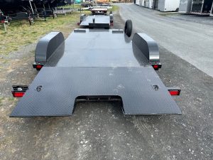 a black trailer is parked on the side of a road .