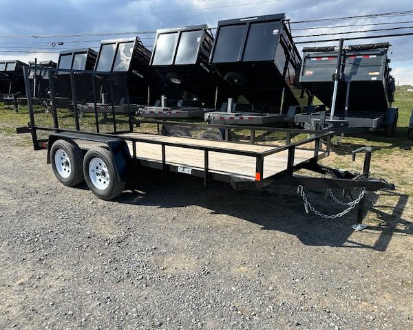 a Car Mate trailer with a wooden deck parked next to a row of dump trailers