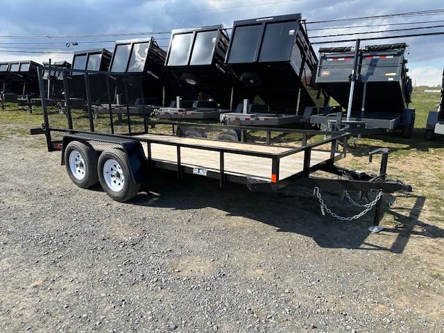 a Car Mate trailer with a wooden deck parked next to a row of dump trailers