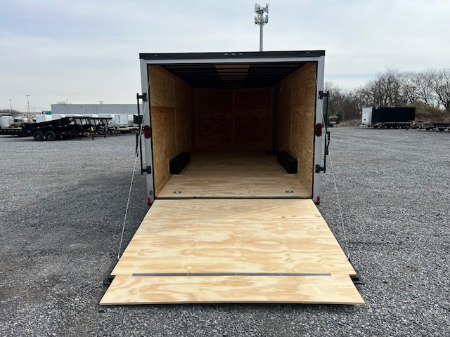 a trailer with a wooden floor is sitting in a gravel lot .